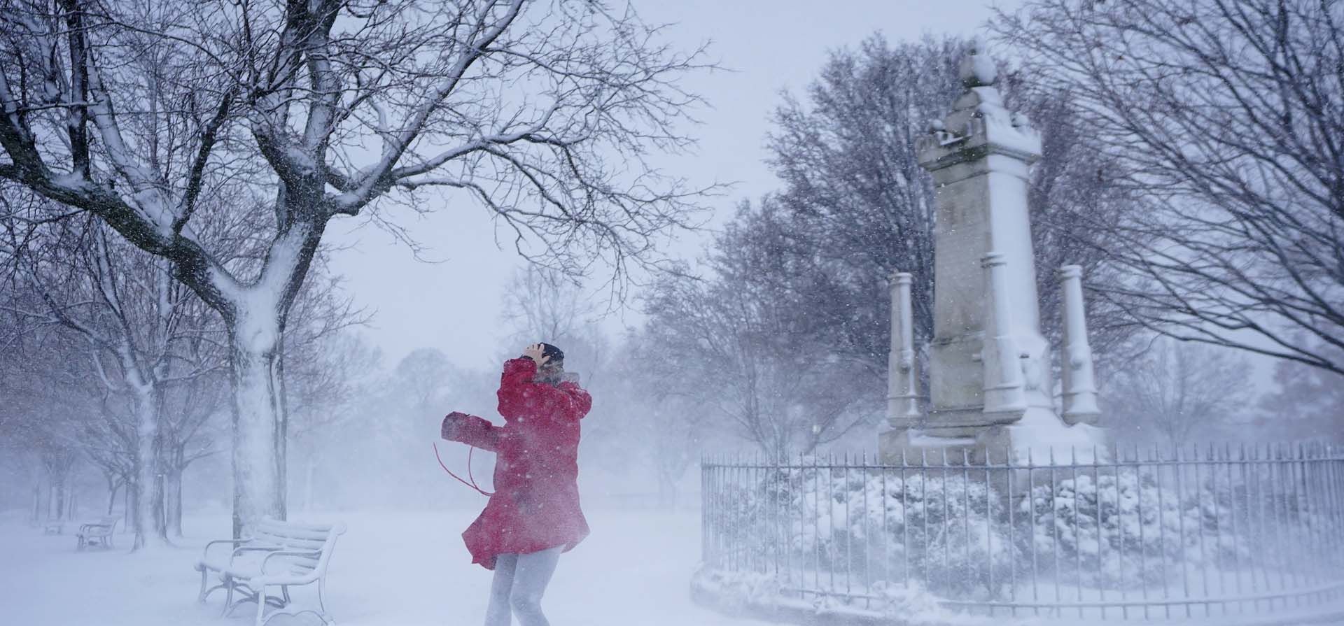 Una mujer se aleja del viento racheado que sopla nieve mientras pasea por Federal Hill Park, en Baltimore. Foto: AP