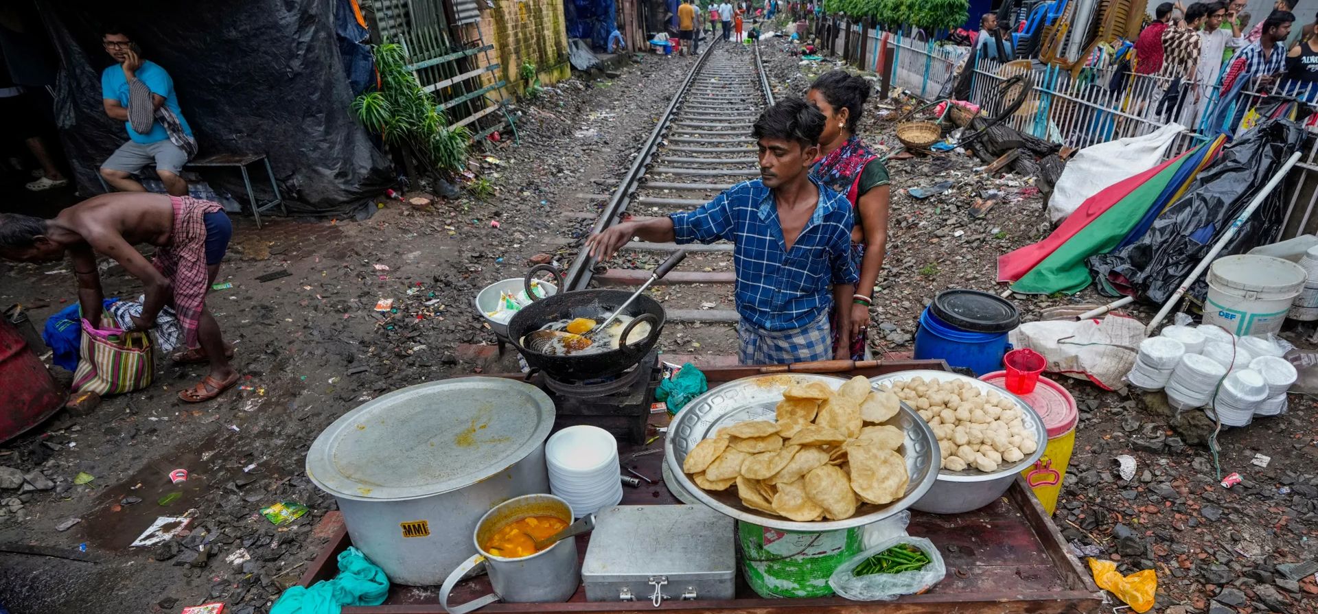 Un vendedor prepara comida en su carrito móvil en una vía férrea después de que los servicios de trenes se suspendieran temporalmente debido a la afluencia de un festival, Calcuta, India. Fotografía: Bikas Das/AP Un vendedor prepara comida en su carrito móvil en una vía férrea después de que los servicios de trenes se suspendieran temporalmente debido a la afluencia de un festival, Calcuta, India. Fotografía: Bikas Das/AP