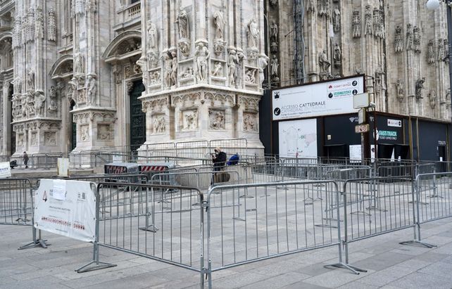 Duomo. Un turista con barbijo de pie junto a la entrada cerrada de la catedral de Milán.