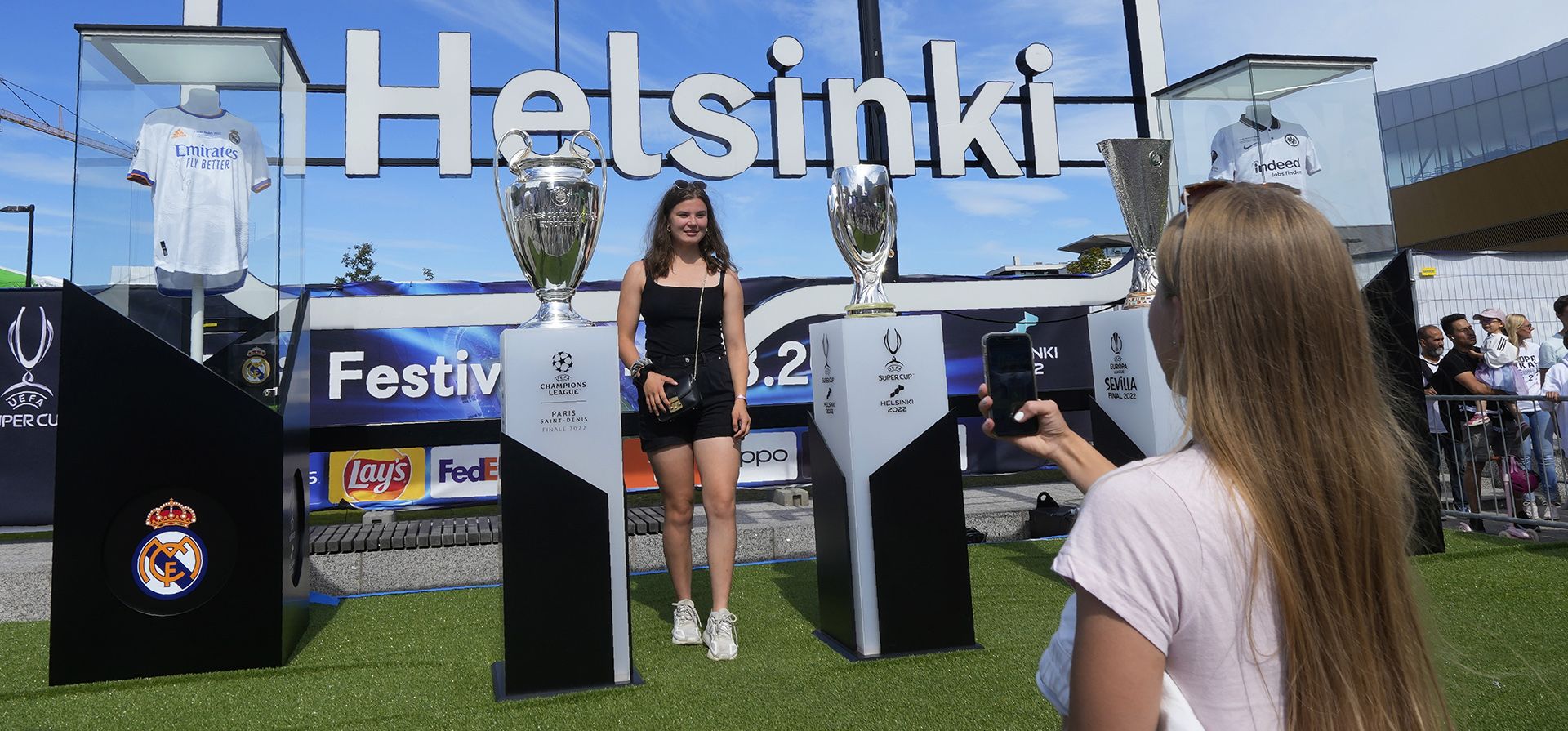 Una joven posa para fotografías junto a una copia del trofeo de la Supercopa en el centro de Helsinki, Finlandia, el miércoles 10 de agosto de 2022. El Real Madrid jugará este miércoles contra el Eintracht Frankfurt en la final de la Supercopa de la UEFA.