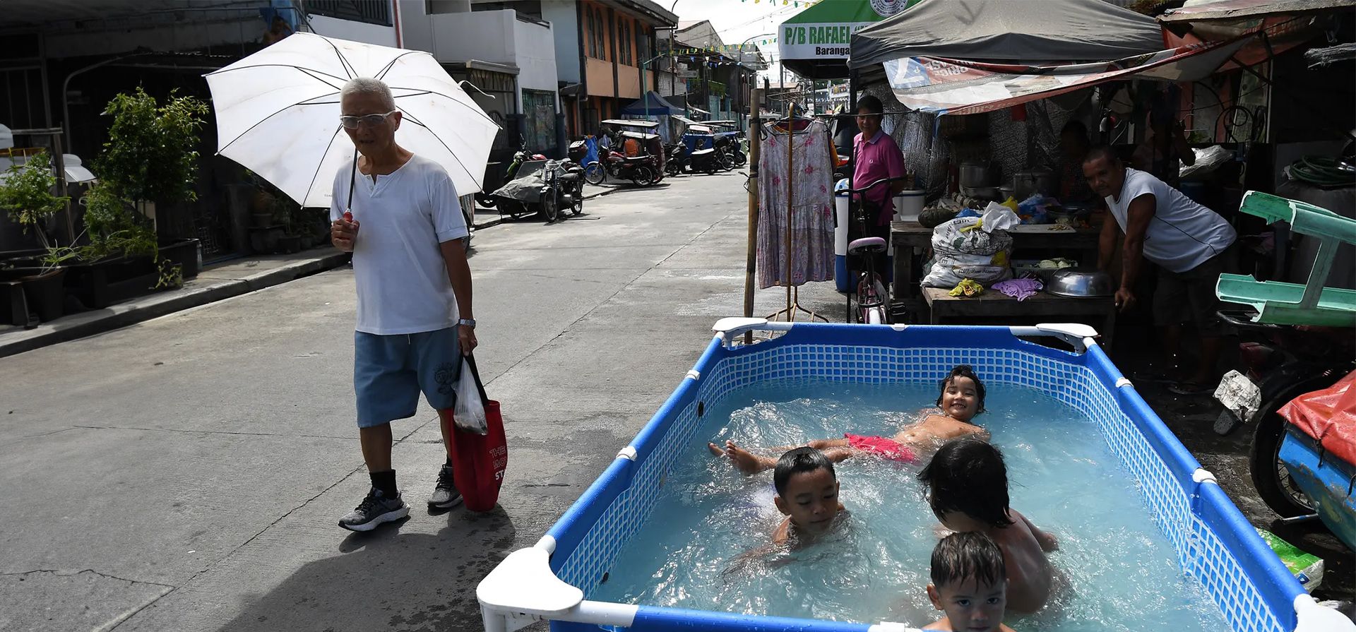 Un hombre pasa junto a unos niños que se refrescan en una piscina infantil instalada en una calle durante la ola de calor de la ciudad, Manila, Filipinas. Fotografía: Ted Aljibe/AFP/Getty Images Un hombre pasa junto a unos niños que se refrescan en una piscina infantil instalada en una calle durante la ola de calor de la ciudad, Manila, Filipinas. Fotografía: Ted Aljibe/AFP/Getty Images