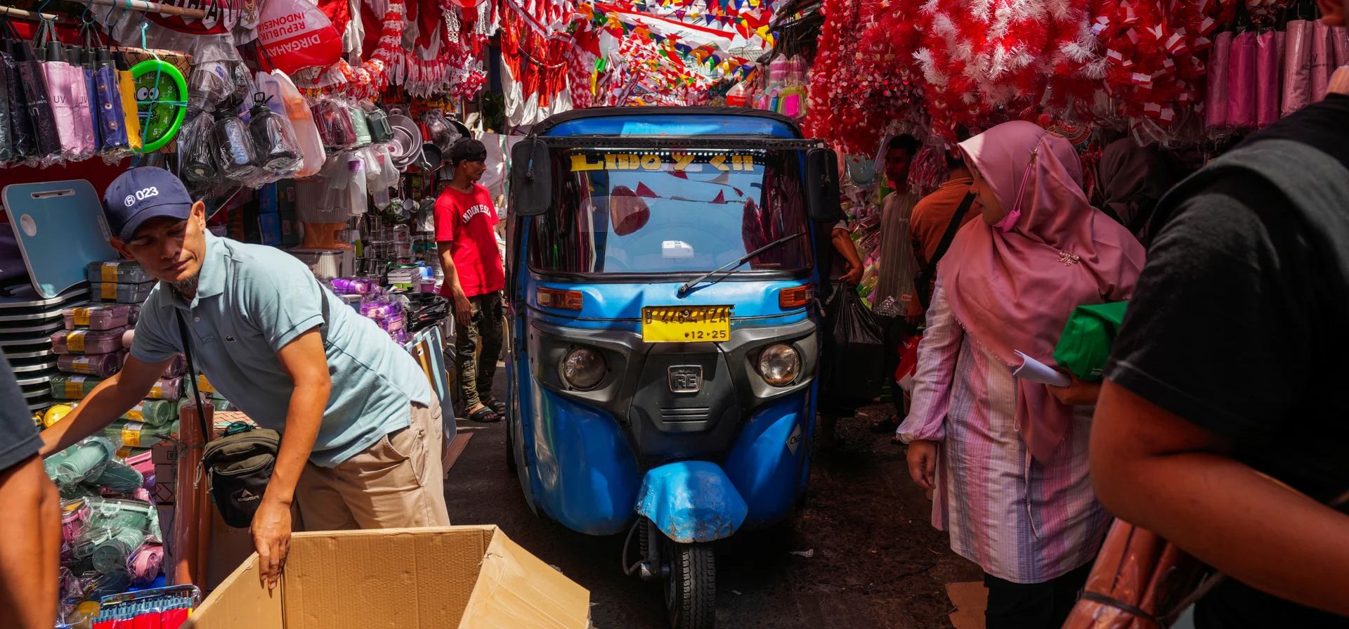 Un vehículo motorizado pasa junto a la gente en un callejón donde los vendedores han exhibido banderas nacionales y material de decoración para la venta antes del aniversario de la independencia del país en Yakarta, Indonesia, el martes 13 de agosto de 2024. (Foto AP/Tatan Syuflana) Un vehículo motorizado pasa junto a la gente en un callejón donde los vendedores han exhibido banderas nacionales y material de decoración para la venta antes del aniversario de la independencia del país en Yakarta, Indonesia, el martes 13 de agosto de 2024. (Foto AP/Tatan Syuflana)