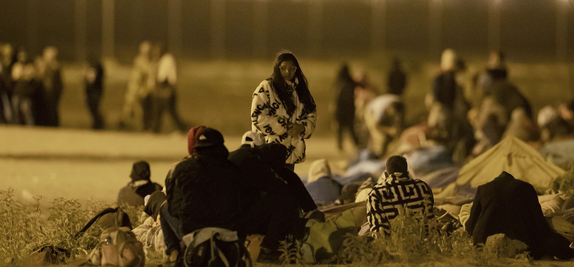Migrantes esperan en una puerta en la valla fronteriza después de cruzar de Ciudad Juárez, México a El Paso, Texas, en las primeras horas del jueves 11 de mayo de 2023. Los migrantes cruzaron la frontera horas antes de que se aplicaran las restricciones de asilo relacionadas con la pandemia, expirará el jueves, por temor a que las nuevas políticas dificulten mucho más la entrada a Estados Unidos. (Foto AP/Andrés Leighton)