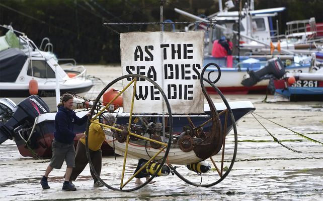Activistas climáticos empujan un barco sobre ruedas con un mensaje en el puerto de St. Ives. Fotografía: Jon Super / AP