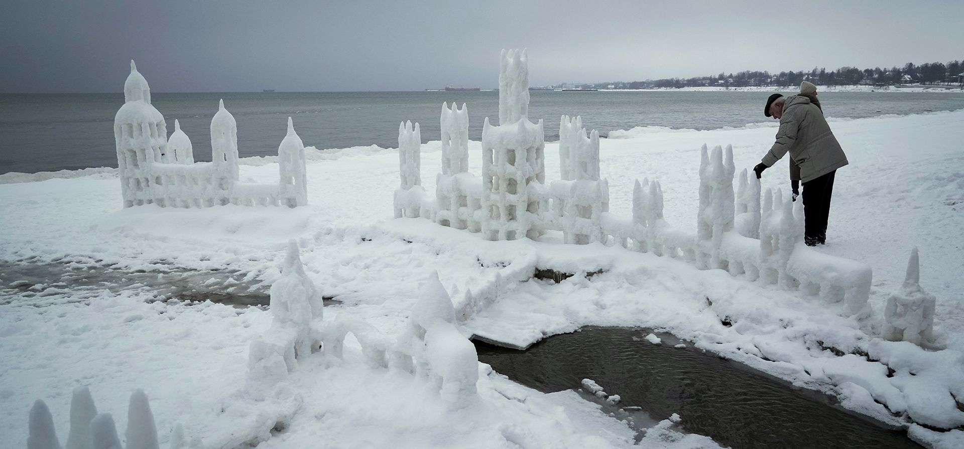 Un hombre mira los castillos de nieve que construyeron los residentes locales en la playa Pirita en el Mar Báltico en Tallin, Estonia, el martes 10 de enero de 2023. (Foto AP/Sergei Grits)