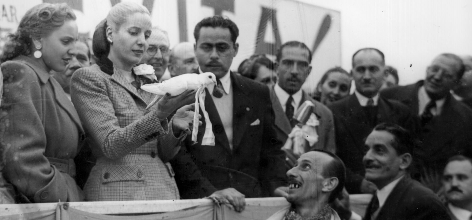 Eva Perón con un paloma blanca en sus manos en el palco de barrio Acindar. Una importante concurrencia de trabajadores, militantes y familias acompañaban el recorrido de la gira, mayo de 1950.
