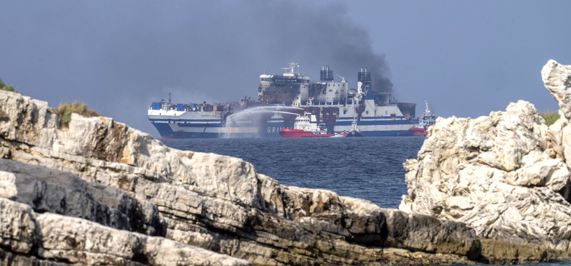 El humo se eleva desde el Euroferry Olympia de bandera italiana, que está en llamas por cuarto día consecutivo, en el mar Jónico cerca de la isla griega de Corfú, el lunes 21 de febrero de 2022. Los rescatistas del servicio de bomberos ampliaron la búsqueda el lunes en el interior un transbordador en llamas anclado frente a la isla griega de Corfú, donde 10 personas siguen desaparecidas.