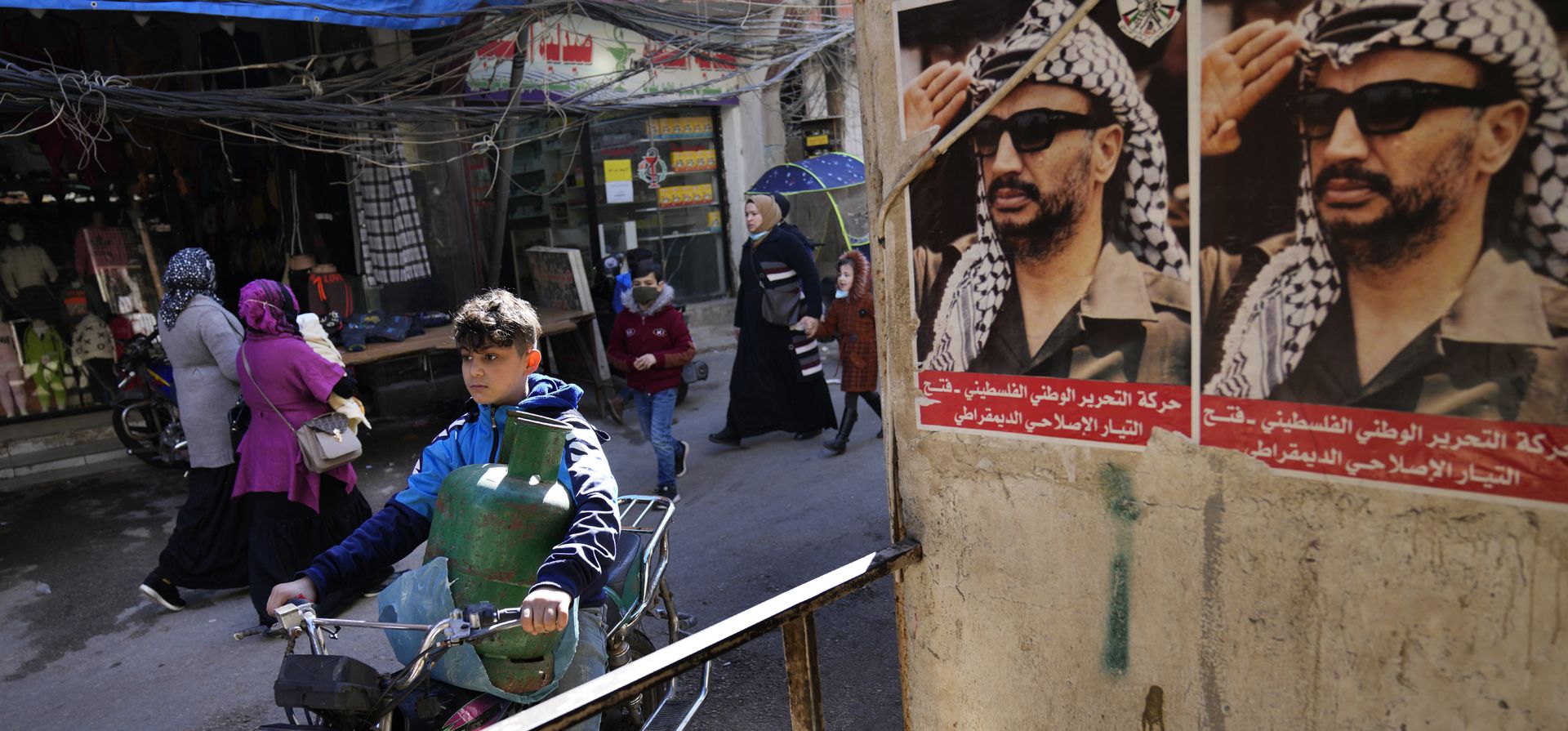 Un niño palestino lleva una bombona de gas en una motocicleta mientras pasa junto a los retratos del difunto líder palestino Yasser Arafat, en el campo de refugiados palestinos de Bourj al-Barajneh, en Beirut, Líbano. La agencia para los refugiados palestinos , o UNRWA, hizo un llamado el miércoles a la comunidad internacional para que done decenas de millones de dólares para ayudar a mejorar las condiciones de vida de los palestinos en el Líbano golpeado por la crisis.