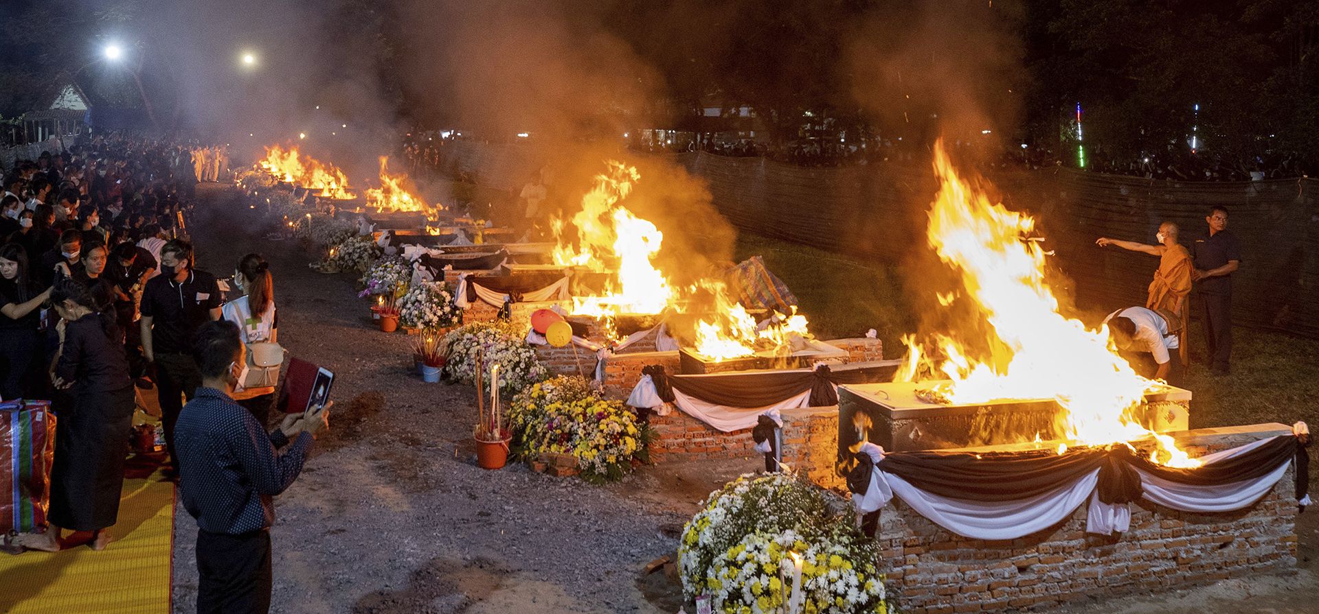 Un monje prende fuego a las piras funerarias de los que murieron en el ataque a la guardería en el templo Wat Rat Samakee en Uthai Sawan, noreste de Tailandia, el martes 11 de octubre de 2022. Un exoficial de policía irrumpió en una guardería en el noreste de Tailandia, el jueves pasado, matando a decenas de niños en edad preescolar y maestros.
