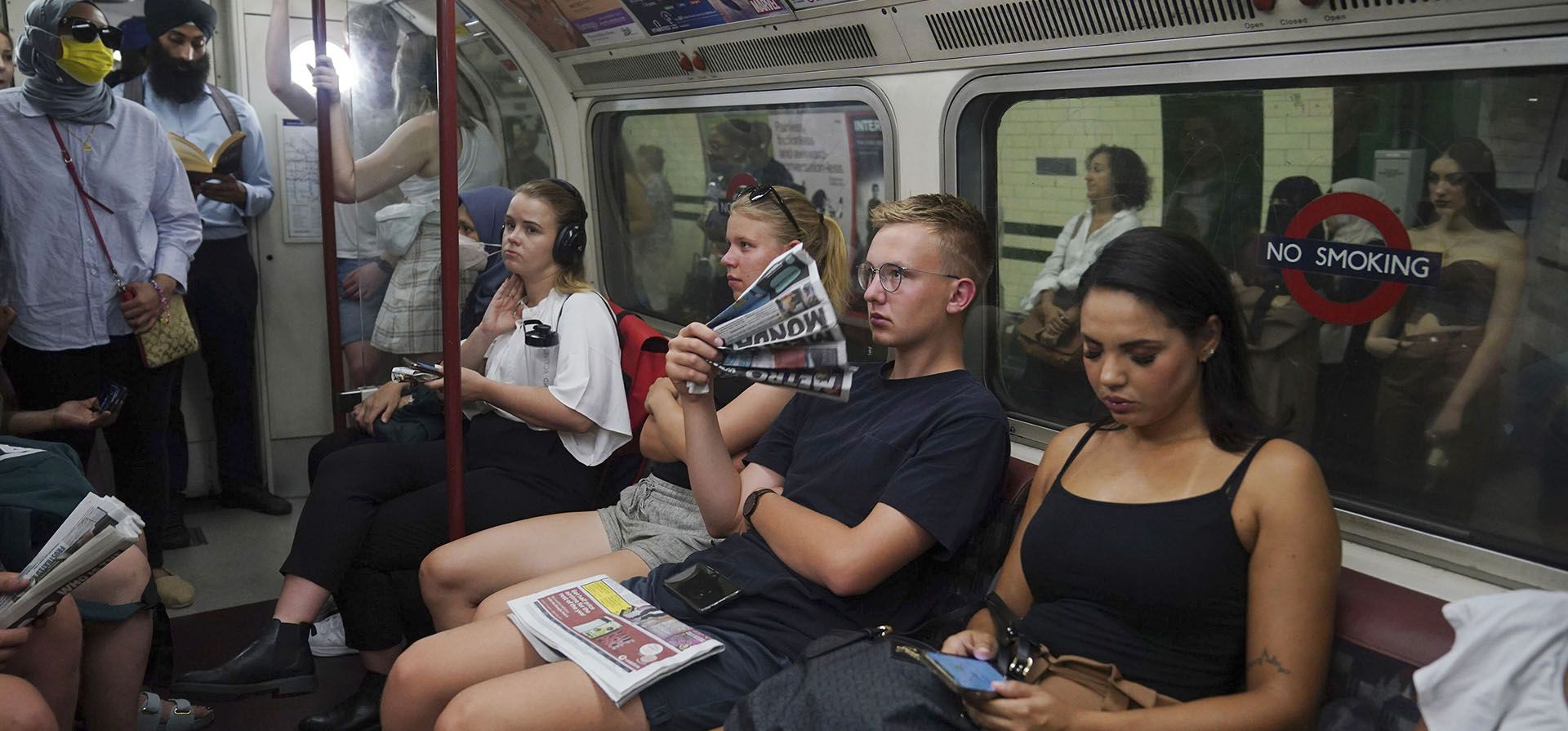 Un hombre usa un periódico como ventilador mientras viaja en la línea Bakerloo en el centro de Londres durante la ola de calor, el lunes 18 de julio de 2022. La primera advertencia de calor extremo de Gran Bretaña está vigente para gran parte de del país debido al clima cálido y seco que azota Europa continental.