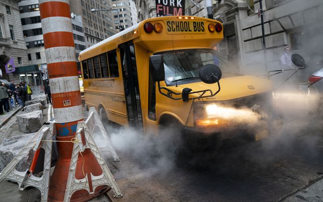 Un autobús escolar pasa a través de un respiradero de vapor en un recorrido matutino, el lunes 4 de octubre de 2021, en el distrito de Manhattan de Nueva York.
