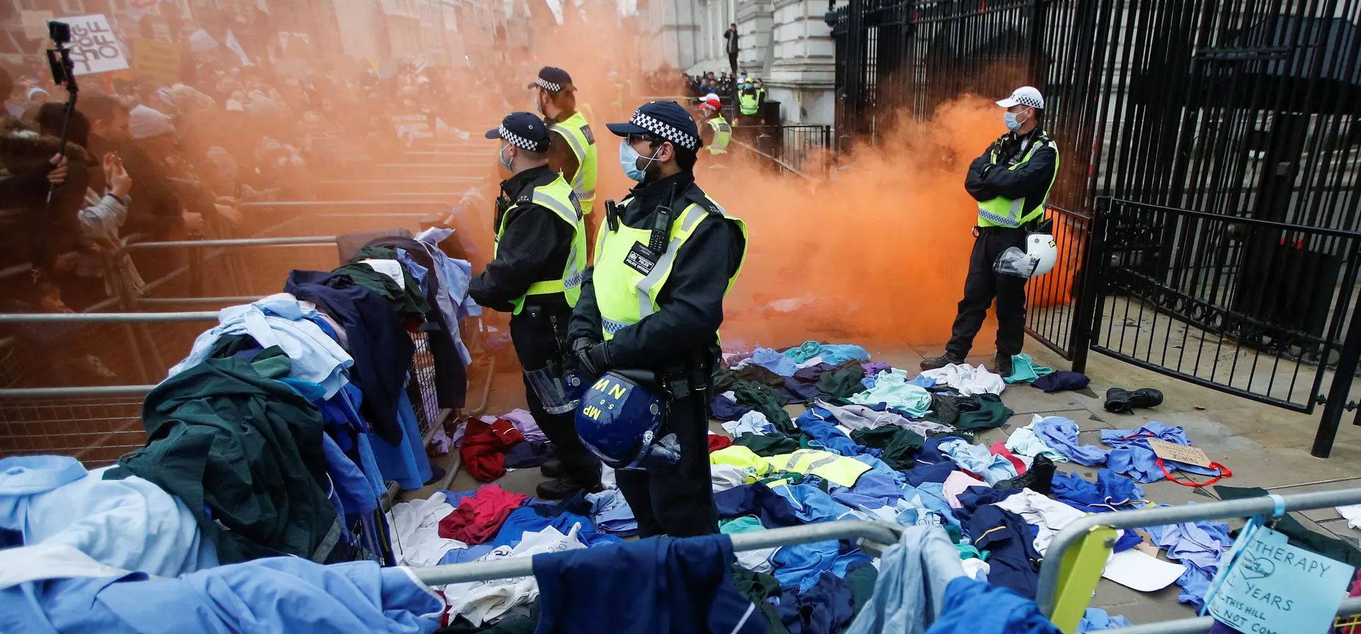 Oficiales de policía se encuentran en medio de las protestas del personal del Instituto Nacional de Salud y manifestantes que se expresan contra las reglas de la vacuna Covid-19 en la entrada de Downing Street.