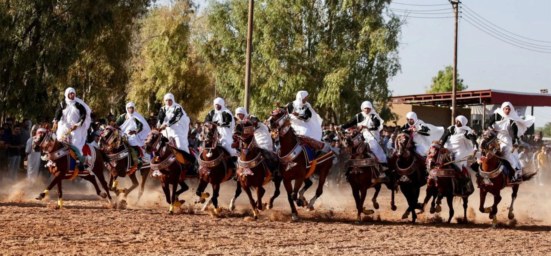 Hombres vestidos con trajes tradicionales montan a caballo durante una carrera de caballos en Misrata, Libia.