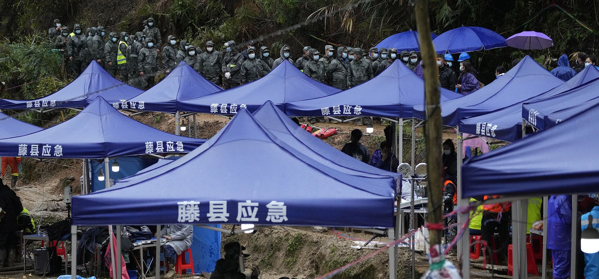 Los trabajadores de búsqueda y rescate se alinean a lo largo de un centro de comando cerca del lugar del accidente del este de China el jueves 24 de marzo de 2022 en la aldea de Molang, en la provincia de Guangxi, suroeste de China. El área de búsqueda se amplió el jueves en una