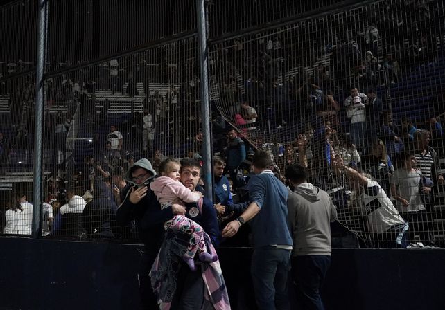 Más que mil palabras. Uno de los tantos simpatizantes que logró zafar de la tribuna con su hija en manos, pasando al campo de juego donde pudieron sentirse más protegidos.