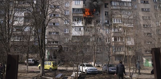 Un residente mira un edificio de apartamentos en llamas después de los bombardeos en Mariupol