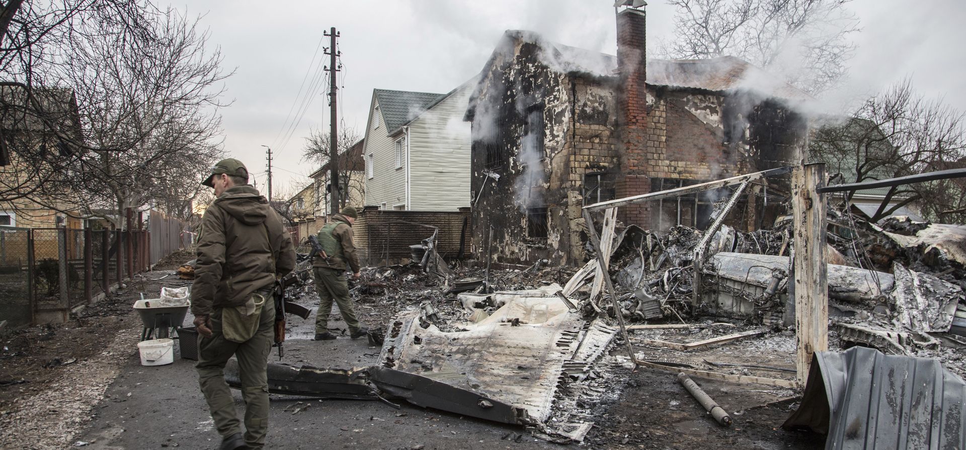 Militares ucranianos caminan frente a los fragmentos de un avión derribado en Kiev, Ucrania, el viernes 25 de febrero de 2022.