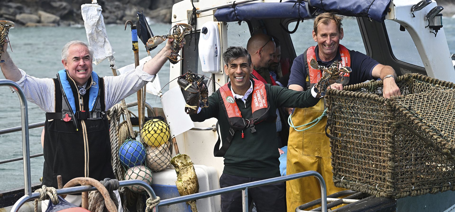 El primer ministro británico, Rishi Sunak, en el centro, y el parlamentario de West Devon, Geoffrey Cox, a la izquierda, viajan en un bote en el puerto de Clovelly, Inglaterra, mientras recolectan nasas de langosta el martes 18 de junio de 2024. (Leon Neal, Pool Photo vía AP El primer ministro británico, Rishi Sunak, en el centro, y el parlamentario de West Devon, Geoffrey Cox, a la izquierda, viajan en un bote en el puerto de Clovelly, Inglaterra, mientras recolectan nasas de langosta el martes 18 de junio de 2024. (Leon Neal, Pool Photo vía AP