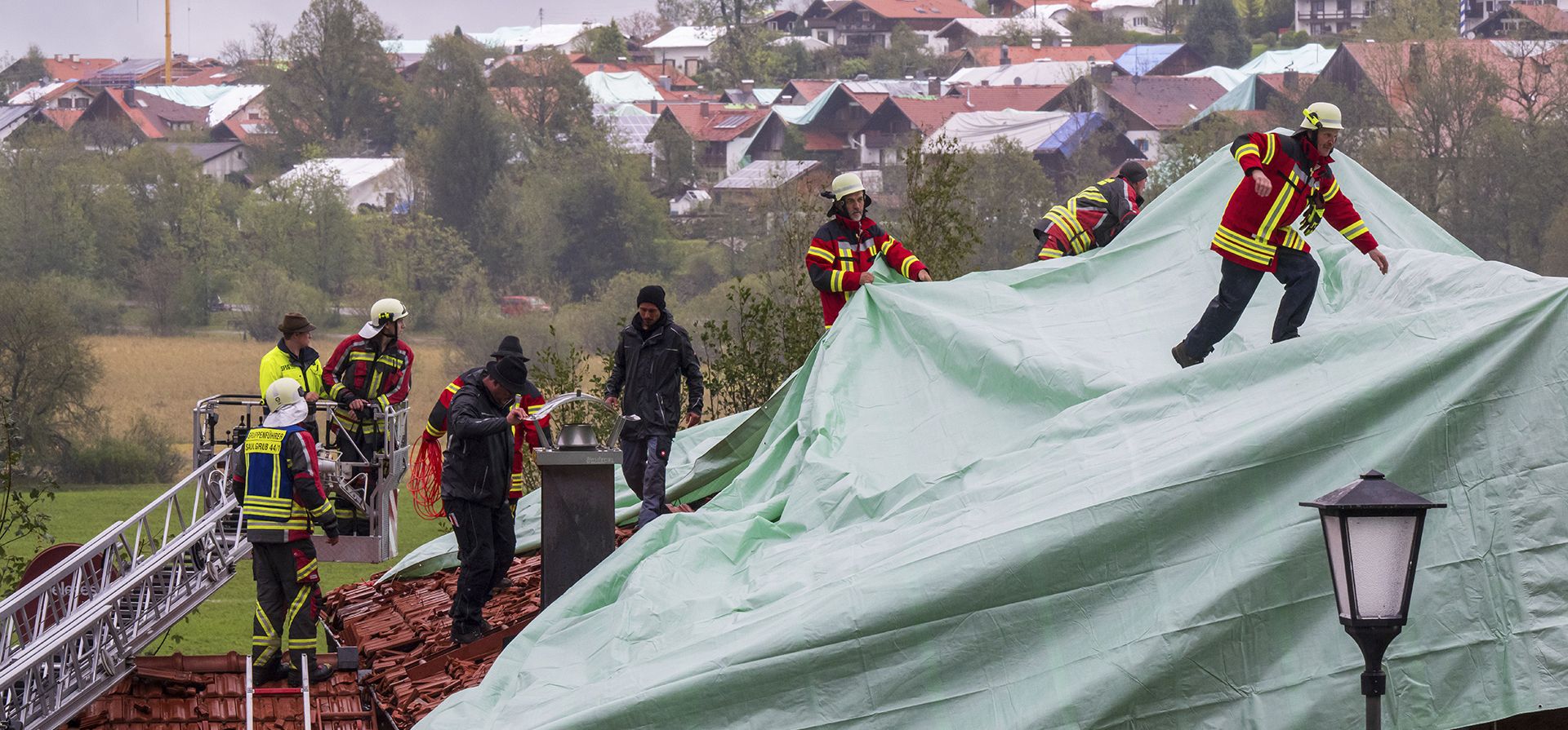 Bomberos aseguran y cubren techos dañados con grandes lonas en Bad Bayersoien, un municipio de unas 1.300 personas en la región de Garmisch-Partenkirchen, Alemania, el lunes 28 de agosto de 2023. Las autoridades del condado dijeron el domingo que Bad Bayersoien fue alcanzado por granizo de hasta 8 centímetros, que dañaron coches estacionados y destrozaron tejas y claraboyas de áticos, mientras que la tormenta también arrancó tejados de algunos edificios. (Peter Kneffel/dpa vía AP) Bomberos aseguran y cubren techos dañados con grandes lonas en Bad Bayersoien, un municipio de unas 1.300 personas en la región de Garmisch-Partenkirchen, Alemania, el lunes 28 de agosto de 2023. Las autoridades del condado dijeron el domingo que Bad Bayersoien fue alcanzado por granizo de hasta 8 centímetros, que dañaron coches estacionados y destrozaron tejas y claraboyas de áticos, mientras que la tormenta también arrancó tejados de algunos edificios. (Peter Kneffel/dpa vía AP)
