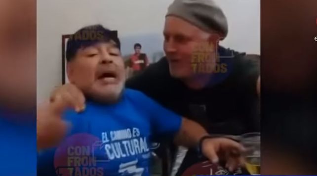 Descuidado. Diego cantando con un amigo y detrás su imagen con la camiseta de Newells. (captura de TV)