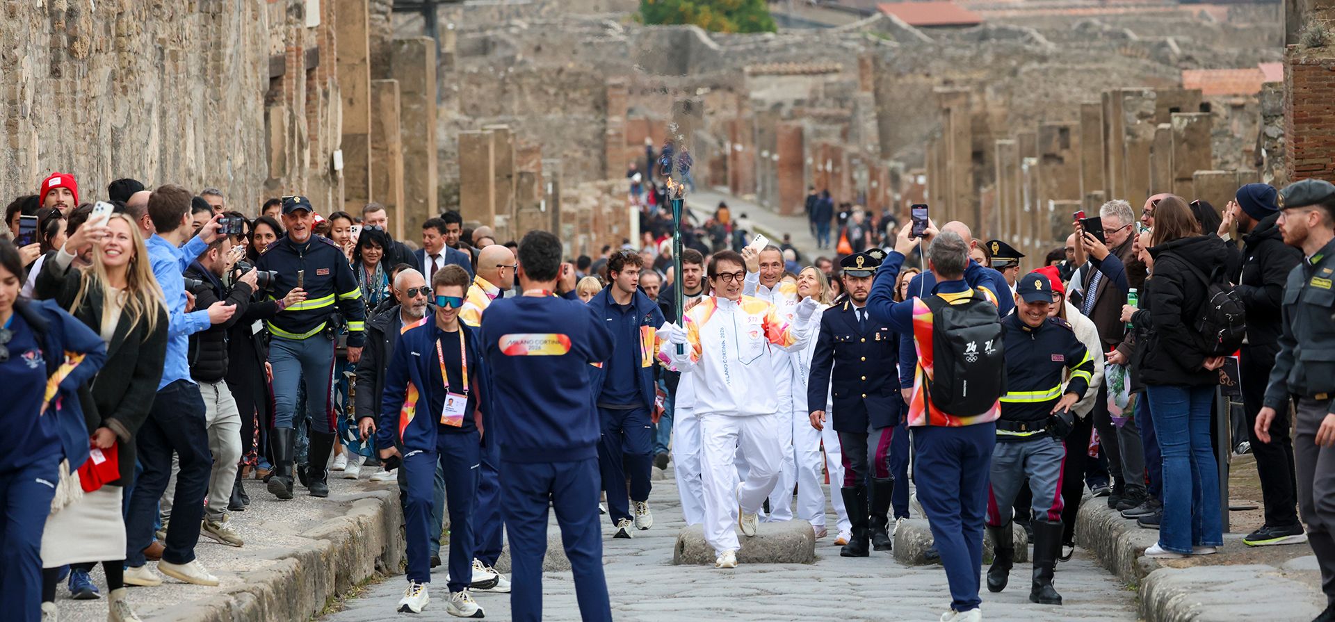 El actor Jackie Chan sostiene la antorcha olímpica a su paso por el Parque Arqueológico de Pompeya, Italia, el lunes 22 de diciembre de 2025. (Alessandro Garofalo/LaPresse vía AP)