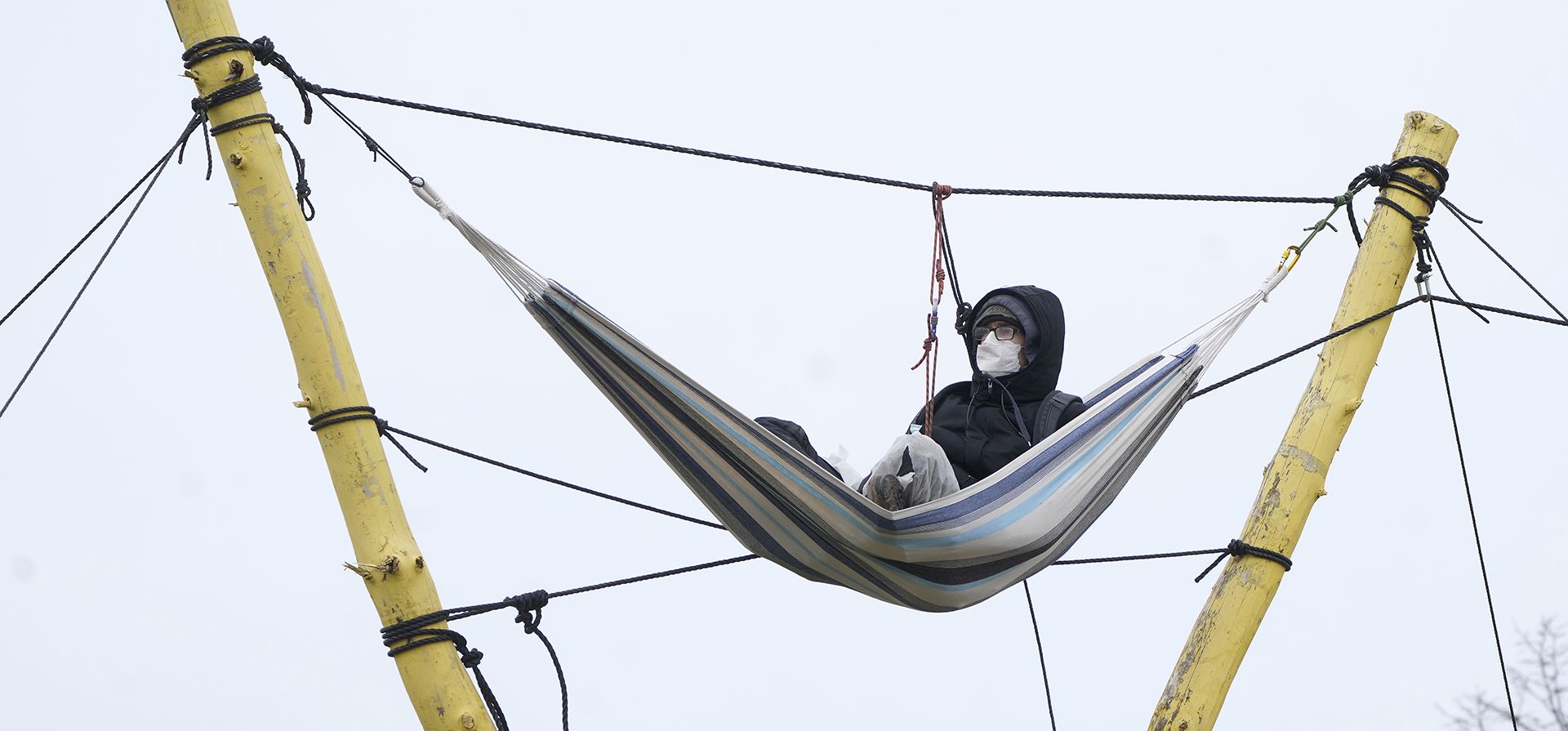 Una persona sentada en una hamaca junto a la mina a cielo abierto de lignito Garzweiler en el pueblo de Luetzerath cerca de Erkelenz, Alemania, el martes 10 de enero de 2023. Un tribunal en Alemania rechazó un último intento de activistas climáticos de quedarse en un pueblo abandonado que se debe despejar para la expansión de una mina de carbón que se ha convertido en un campo de batalla entre el gobierno y los ambientalistas. (Foto AP/Michael Probst)