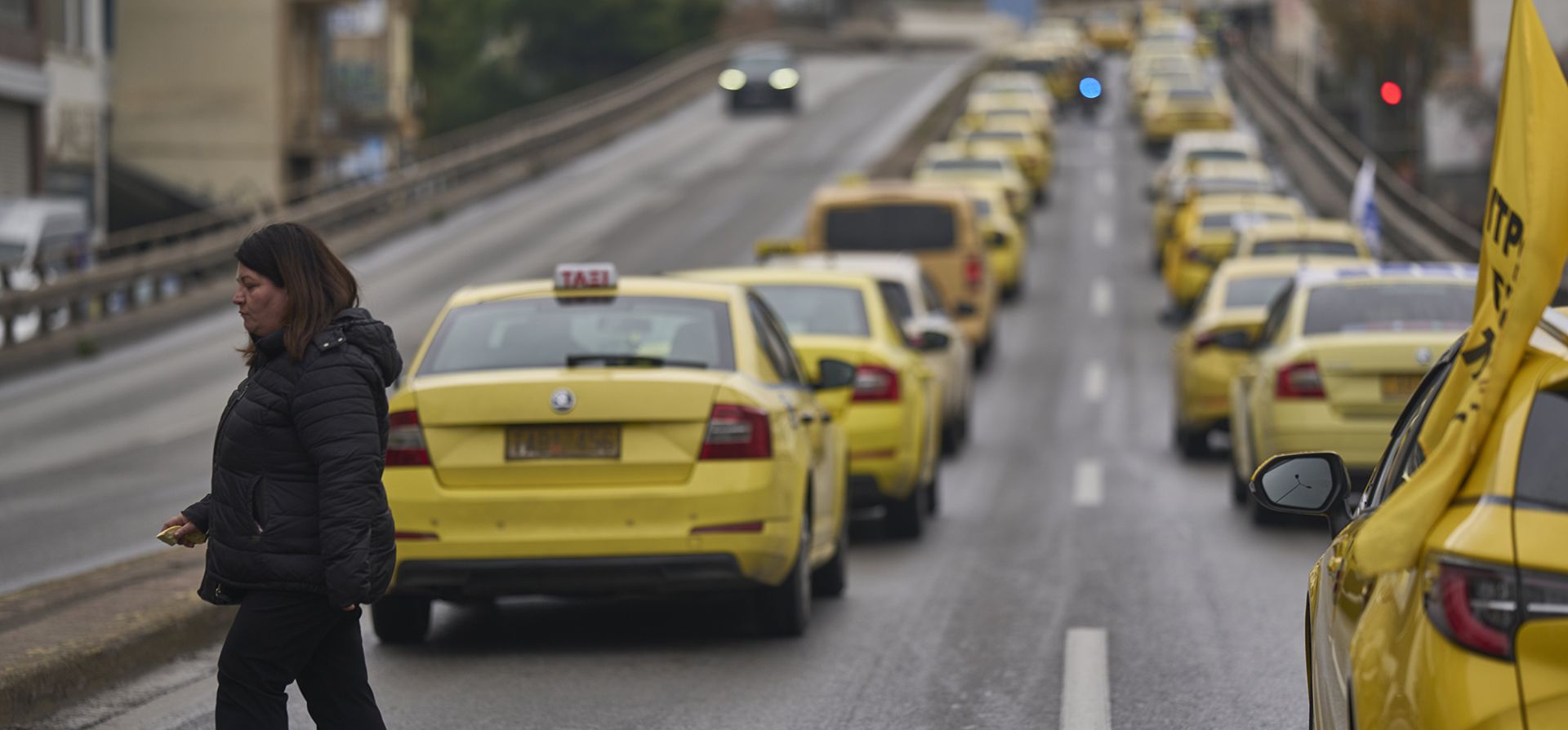 Una mujer camina por una calle mientras los taxistas en huelga se manifiestan en Atenas, en protesta contra una disposición del nuevo Código de Tráfico que prohíbe los taxis en los carriles para autobuses, el miércoles 19 de febrero de 2025. (Foto AP/Petros Giannakouris) Una mujer camina por una calle mientras los taxistas en huelga se manifiestan en Atenas, en protesta contra una disposición del nuevo Código de Tráfico que prohíbe los taxis en los carriles para autobuses, el miércoles 19 de febrero de 2025. (Foto AP/Petros Giannakouris)