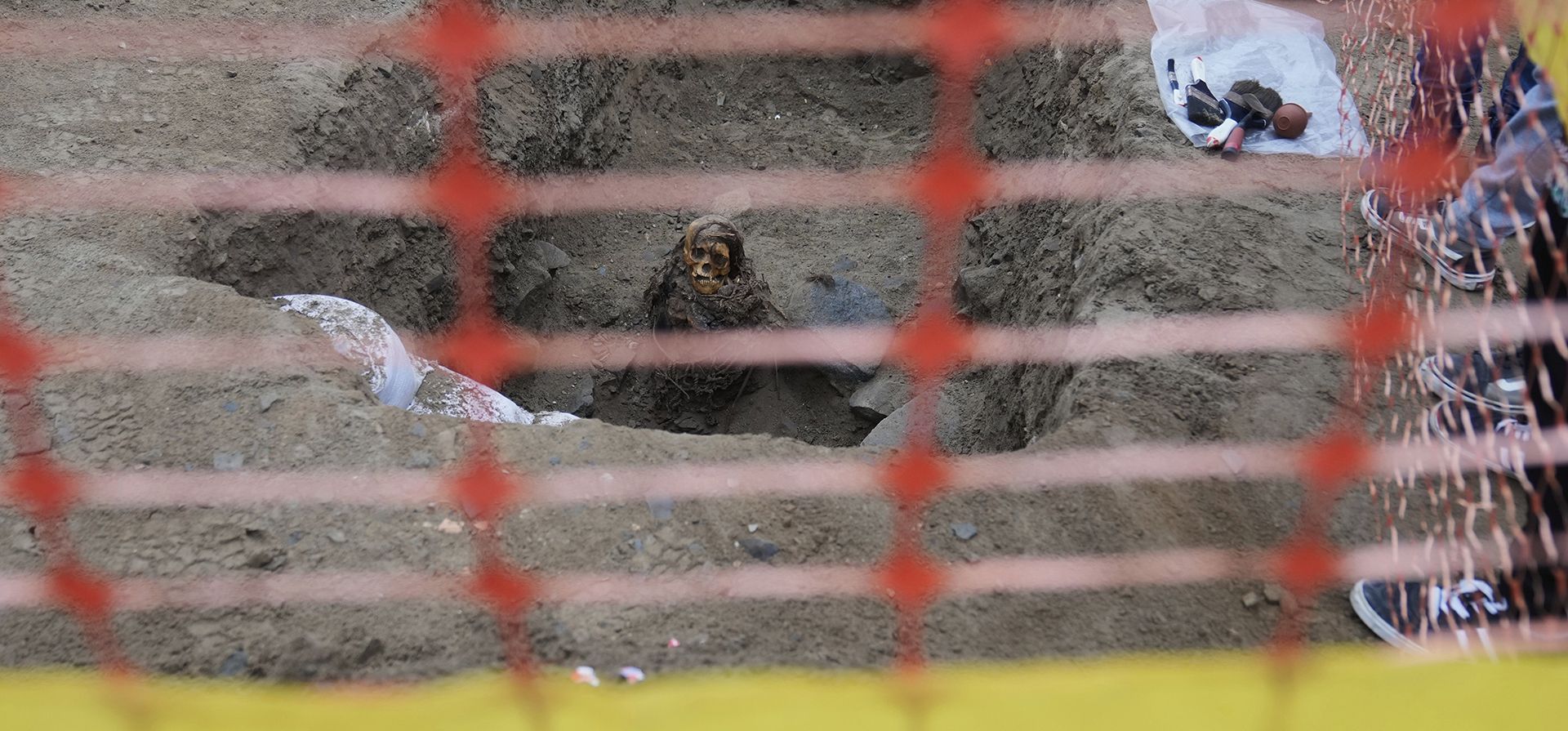 Una momia antigua que los arqueólogos identifican como femenina y de la cultura preincaica Chancay es excavada parcialmente después de ser descubierta por trabajadores de la ciudad que excavaban una línea de gas natural en el distrito de Puente Piedra, en las afueras de Lima, Perú, el miércoles 18 de junio de 2025. (Foto AP/Martin Mejia)