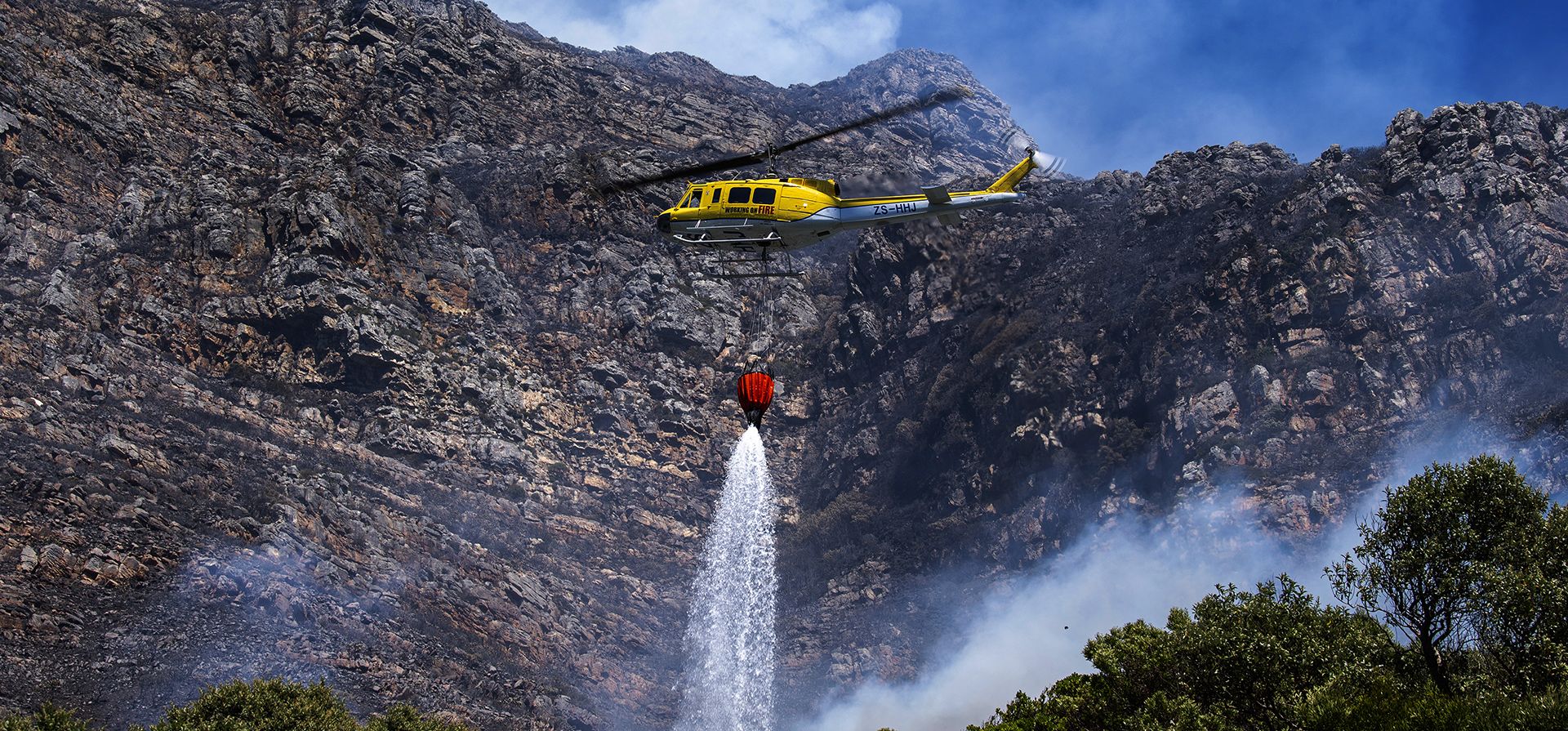 Un helicóptero de extinción de incendios combate un incendio de vegetación en las laderas de Simon Un helicóptero de extinción de incendios combate un incendio de vegetación en las laderas de Simon