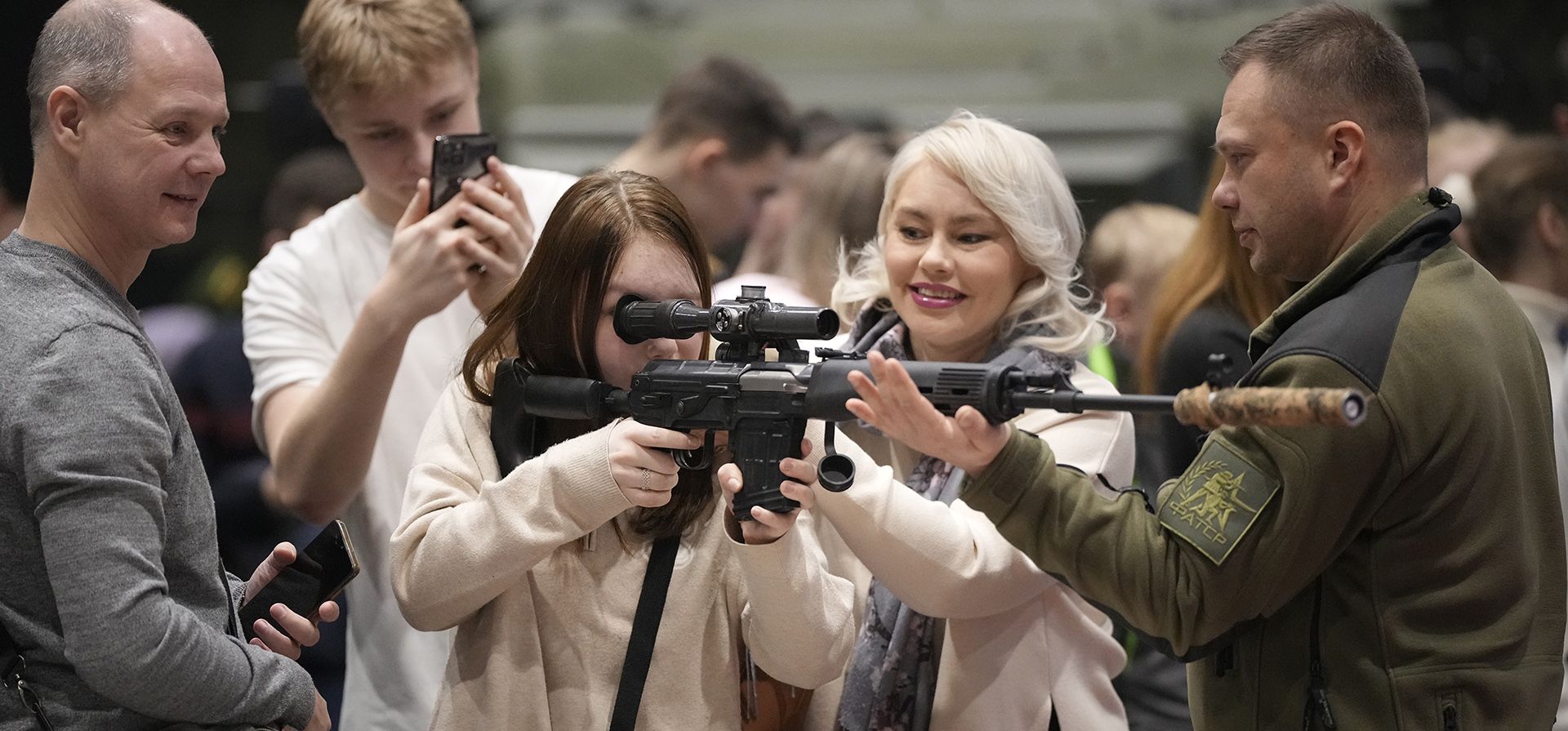 Una niña apunta con una pistola de francotirador en un campo de tiro láser en el festival patriótico Una niña apunta con una pistola de francotirador en un campo de tiro láser en el festival patriótico