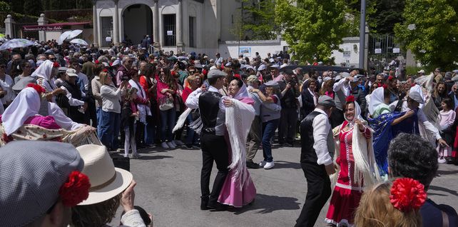 Personas vestidas con trajes regionales de Chulapa y Chulapo bailan en la calle durante las festividades de San Isidro en Madrid