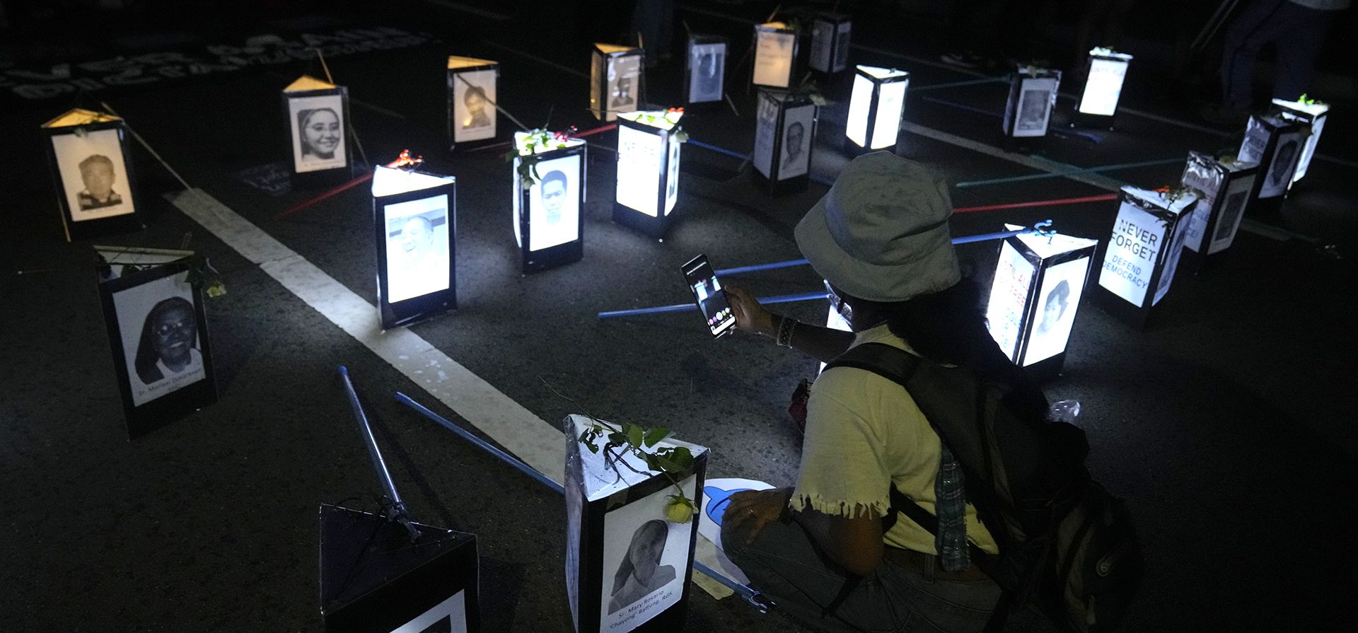 Una mujer toma fotografías de lámparas con imágenes de personas de la iglesia que lucharon durante la ley marcial en conmemoración de su 50º aniversario en la Universidad de Filipinas en Metro Manila, Filipinas, el miércoles 21 de septiembre de 2022.