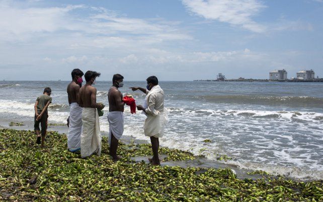 Un grupo de jóvenes realizan los últimos ritos por su madre fallecida en la costa del Mar Arábigo en Kochi, estado de Kerala, India, el lunes 23 de agosto de 2021.