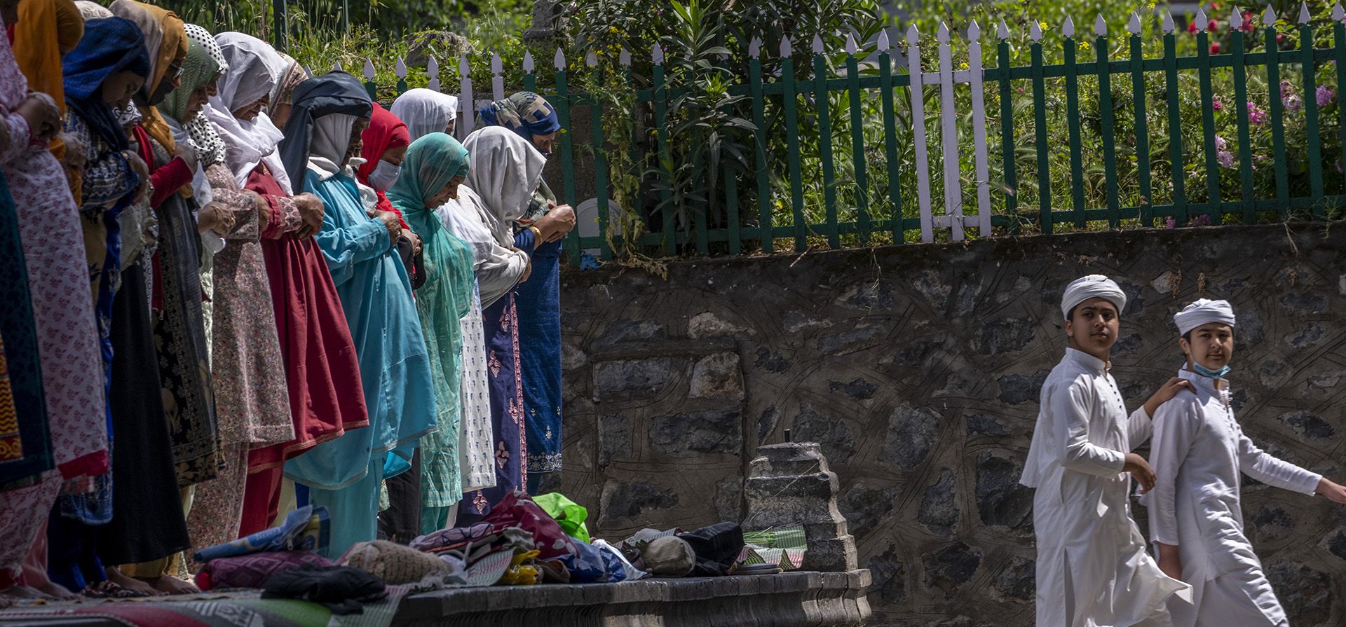 Niños de Cachemira observan a mujeres ofrecer oraciones fuera de la mezquita Shah-e-Hamdan, una de las más antiguas de Cachemira, en Jumat-ul-Vida, el último viernes de Ramadán, en Srinagar, Cachemira india, el viernes 29 de abril de 2022.