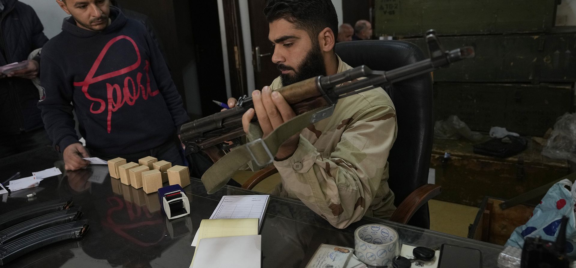 Un combatiente sirio, a la derecha, recibe un AK-47 de un miembro del ejército del derrocado presidente sirio Bashar Assad, luego de que se registrara con los rebeldes sirios como parte de un Un combatiente sirio, a la derecha, recibe un AK-47 de un miembro del ejército del derrocado presidente sirio Bashar Assad, luego de que se registrara con los rebeldes sirios como parte de un