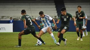 El juvenil rojinegro Valentino Acuña maniobra entre dos rivales bolivianos.