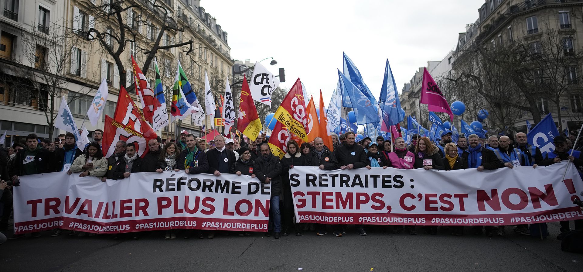 Los líderes sindicales encabezan una manifestación detrás de una pancarta que dice
