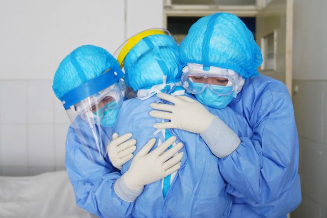 Hospital. Un m&eacute;dico y una enfermera abrazan con cuidado a un paciente puesto en cuarentena.