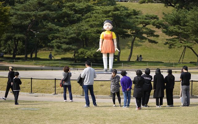 Visitantes miran un modelo de la muñeca llamada Younghee que aparece en la serie de Netflix Squid Game que se exhibe en el parque olímpico en Seúl
