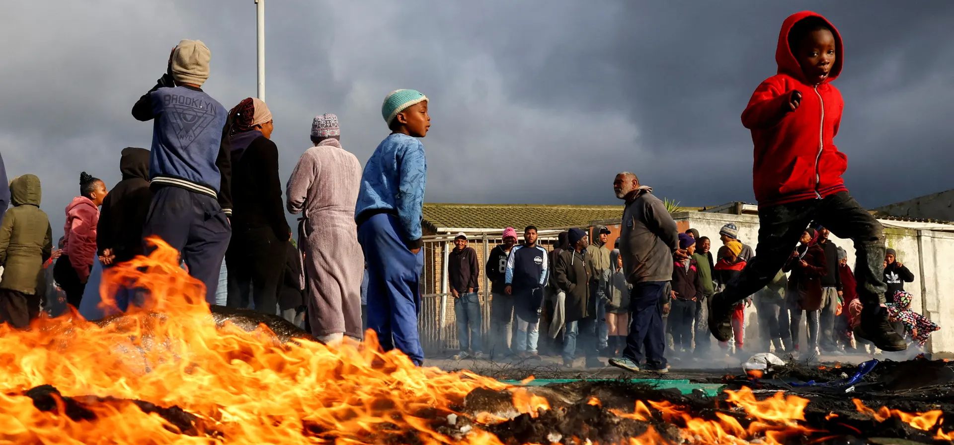 Ciudad del Cabo, Sudáfrica. Un niño pasa corriendo junto a una barricada en llamas durante una protesta por la vivienda de los residentes de Overcome Heights, un asentamiento informal. Fotografía: Esa Alexander/Reuters Ciudad del Cabo, Sudáfrica. Un niño pasa corriendo junto a una barricada en llamas durante una protesta por la vivienda de los residentes de Overcome Heights, un asentamiento informal. Fotografía: Esa Alexander/Reuters