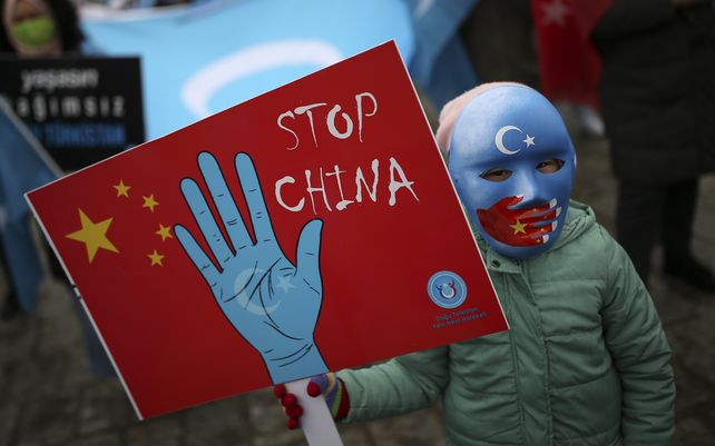 Un niño con mascara de la comunidad uigur que vive en Turquía sostiene una pancarta anti-China durante una protesta contra la visita del ministro de Relaciones Exteriores de China