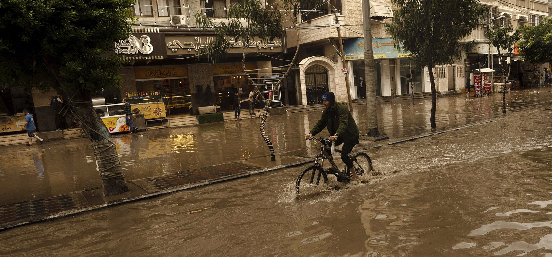 Un joven monta su bicicleta en una calle inundada durante las fuertes lluvias en la ciudad de Gaza, el martes 8 de noviembre de 2022. Las fuertes lluvias causaron inundaciones repentinas en la Franja de Gaza el martes, donde la infraestructura obsoleta a menudo evita que las aguas retrocedan, lo que prolonga el daño.