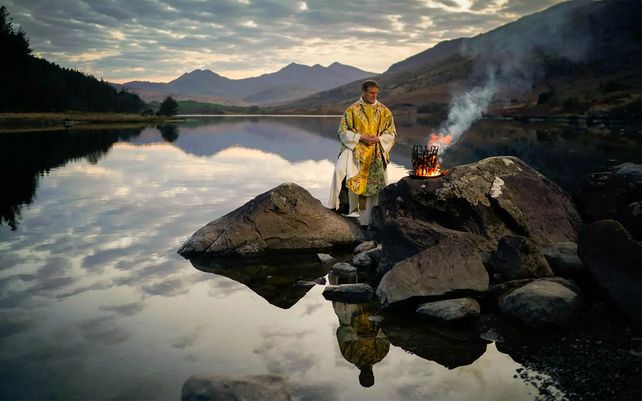 El reverendo Stuart Elliott bendice el nuevo fuego como parte de su Servicio de Nueva Luz para la víspera de Pascua en la costa de Llynnau Mymbyr en Snowdonia