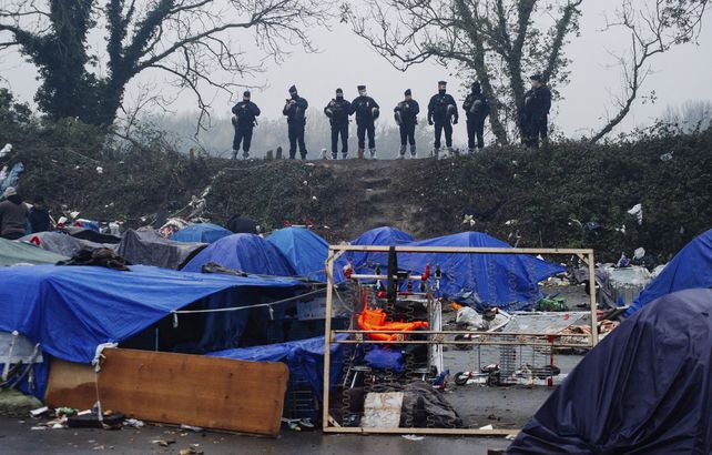 Fuerzas policiales observan el campamento improvisado para migrantes en Grande-Synthe