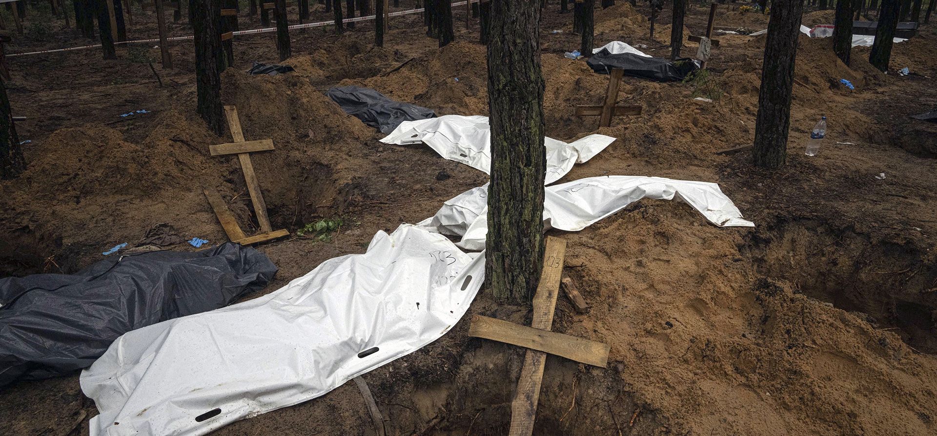 Bolsas con cadáveres se ven durante la exhumación en el área recientemente recuperada de Izium, Ucrania, el viernes 23 de septiembre de 2022. Las autoridades ucranianas descubrieron un sitio de entierro masivo cerca de la ciudad recuperada de Izium que contenía cientos de tumbas. 