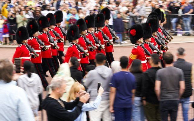 Residentes y turistas ven la ceremonia del cambio de guardia en el Palacio de Buckingham, Londres, que se lleva a cabo por primera vez desde el inicio de la pandemia de coronavirus.
