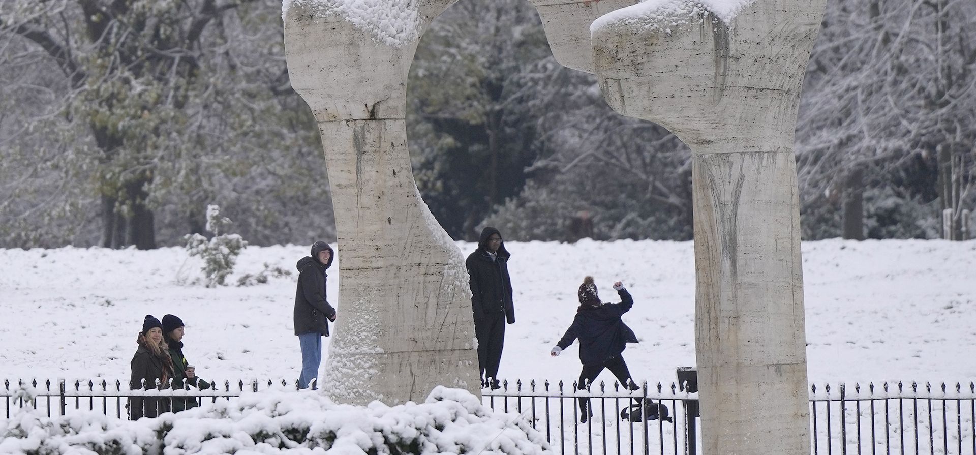 La gente juega con la nieve junto a una escultura titulada 