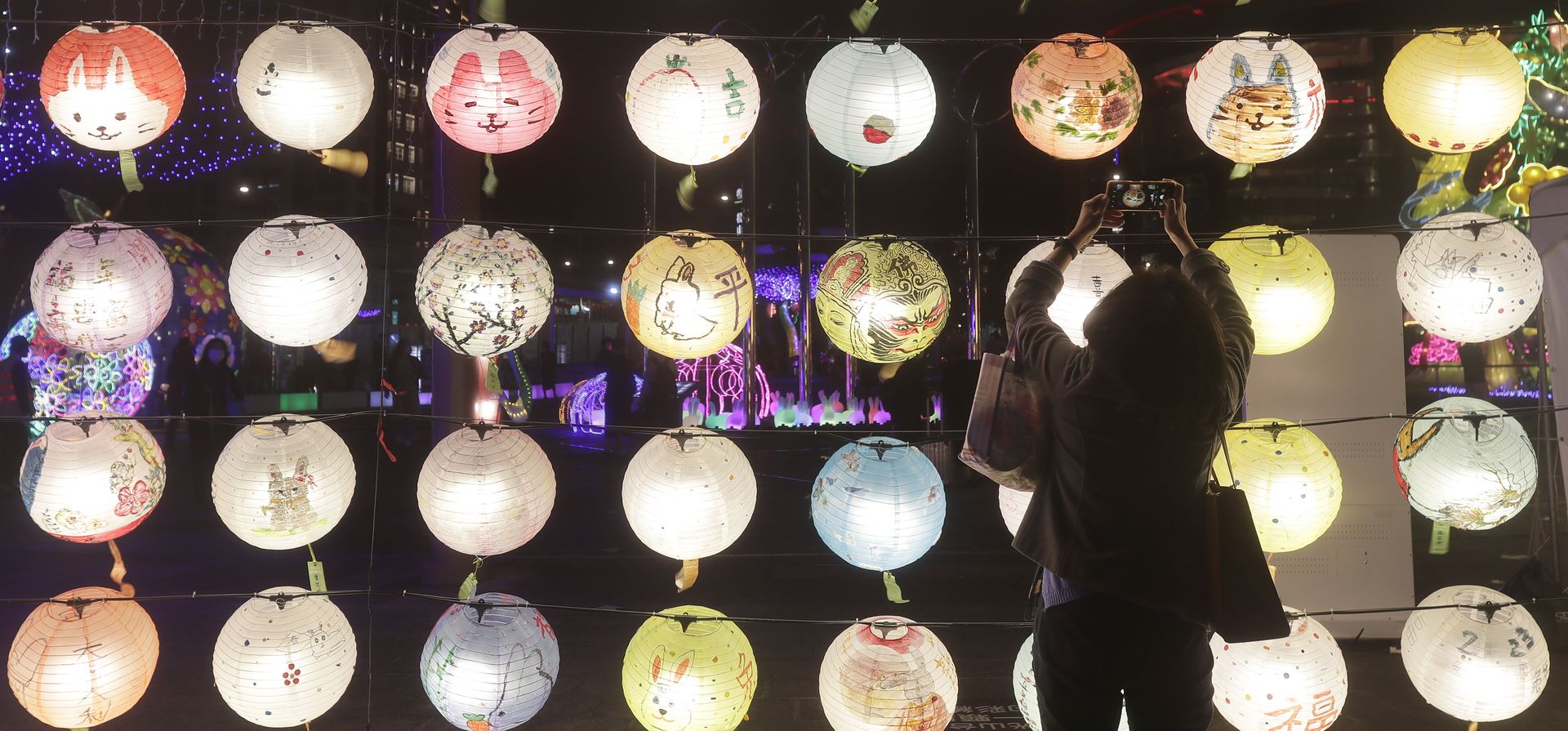 Una mujer toma fotos con linternas durante el Festival de las Linternas, que marca el final de las celebraciones del Año Nuevo lunar chino, en Taipei, Taiwán, el lunes 13 de febrero de 2023. (Foto AP/Chiang Ying-ying)