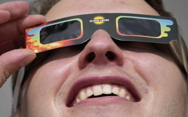 Un hombre usa anteojos especiales para ver el eclipse solar parcial en Trafalgar Square en Londres.