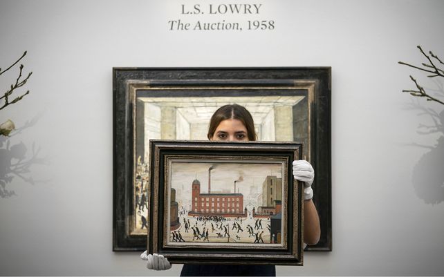 Un miembro del personal de Sothebys sostiene la obra de arte Mill Scene de Laurence Stephen Lowry